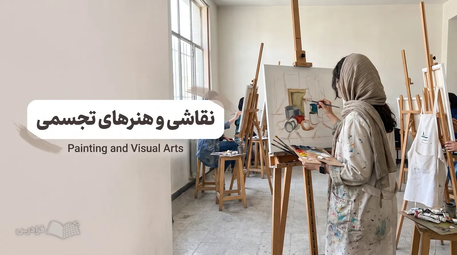 کارگاه نقاشی دانشگاهی با دانشجویی که روی بوم ناتمام رنگ روغن کار می‌کند.